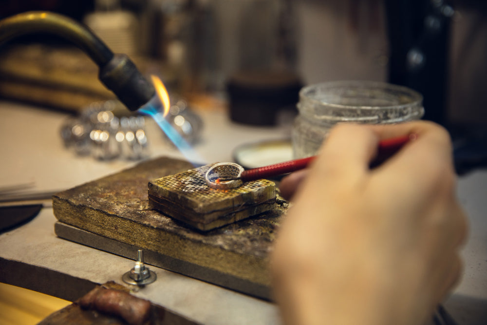  Jeweler crafts a white gold ring, showcasing the meticulous process behind Naude Bourn’s high-end, handcrafted artisan jewelry, highlighting sustainable craftsmanship and luxury design.